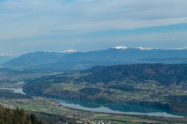 Avusturya, Carinthia 'daki Sinacher Gupf' a giden Rosental Vadisi 'ndeki Drava nehrinin manzarası. İlkbaharın başında orman. Hohe Tauern dağ sırası arka tarafta görülebilir. Güneşli bir gün. Koşun!