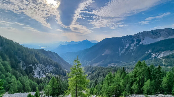 Scenic view on the alpine mountain chains and woodland of the Karawanks in Carinthia, Austria. Peaks are shrouded in morning fog. Mystical vibes. Ssunny day. Serenity. View from Ferlacher Spitze, Alps