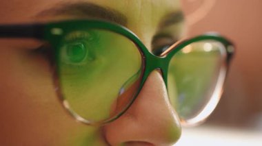 Bilgisayar ekranına odaklanmış programcı kadın. Gözlükler üzerinde geç ekran bilgisayar yansıması üzerinde çalış. İnternet kullanarak, izleyerek, çalışarak..