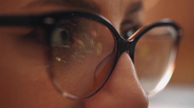 Odaklanmış iş kadınına yakın çekim bilgisayar gözlüğü takıyor bilgisayar yansıtmalı bilgisayar ekranına bakıyor. İnternet kullanan, okuyan, izleyen, şekillendiren, analiz eden, geç saatlere kadar çalışan bir kadın.