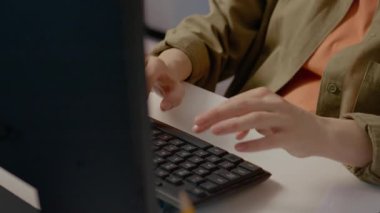 Profesyonel kadın masaüstü bilgisayarında dikkatlice çalışıyor, kod yazarken klavyeye odaklanıyor veya parmak hareketleriyle belge yazıyor