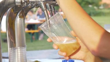 Bir köyün festivalinde sarışının birasına çakan bir kızın yakın çekimi.