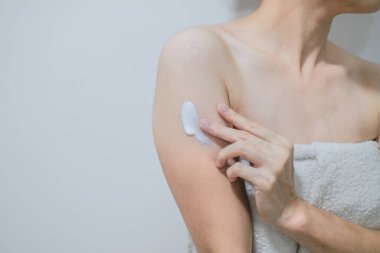 Kadın krem sürüyor, koluna krem sürüyor, beyaz arka plan, güzellik konsepti..