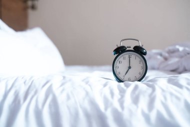 Beyaz yatakta çalar saat. sabah vakti.