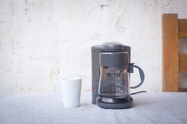 Kahve öğütücüsü ve beyaz arka planlı bir fincan. Tasarım için alanı kopyala. Sabah konsepti.