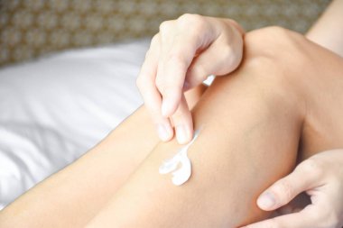 Woman applying cream,lotion on leg. Beauty concept. clipart