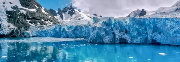 Panoramic view of the beautiful glacier face and dramatic, snowcapped mountains in the Drygalski Fjord on South Georgia Island in the South Atlantic Ocean.