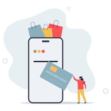 Bayan alışveriş çantasından kıyafet satın alıyor. Ödeme için cep telefonuna kredi kartı takıyor..