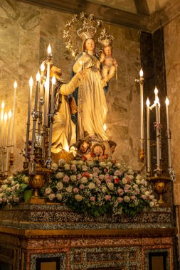 Meryem ve çocuğun heykeli ve yanan mumlarla dolu dini bir arka plan.