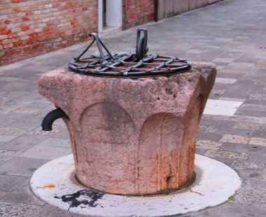 Old water well with iron grille in Venice, Italy. Street scene, old brick. High quality picture for postcards.