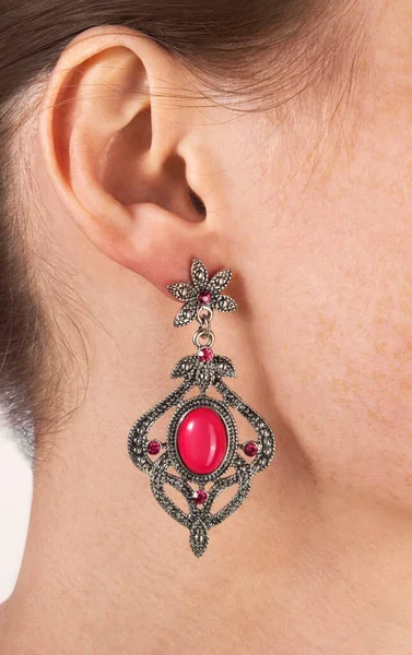 Luxurious vintage silver earring with pink gemstones on woman\'s ear, close up.