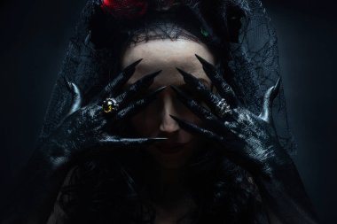 Pençeli ellerinin arkasında yüzünü saklayan Meksikalı cadı ya da büyücü portresi. Cadılar Bayramı ve korku konsepti.