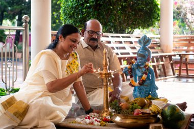 A Picture of middle aged malayali man and woman making Vishu kani clipart