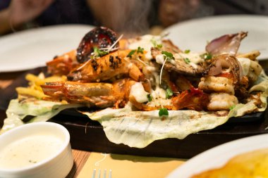 Karidesli, balıklı, ıstakozlu, mürekkepbalıklı, sebzeli ve pirinçli karışık deniz ürünleri cızırtısı resmi.