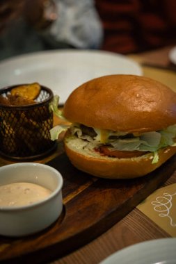 Soslu tavuk burger ve patates cipsi resmi.