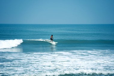 Kerala, Hindistan 'da Varkala Sahili' nde temiz bir dalgada sörf yapan bir adam. Sony Alpha A7 3 aynasız kameraya yakalanmış. Sahil macera sporlarının heyecanını ve güzelliğini gözler önüne seriyor.
