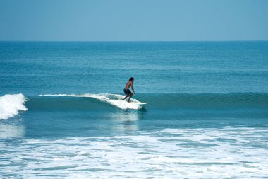 Kerala, Hindistan 'da Varkala Sahili' nde temiz bir dalgada sörf yapan bir adam. Sony Alpha A7 3 aynasız kameraya yakalanmış. Sahil macera sporlarının heyecanını ve güzelliğini gözler önüne seriyor.