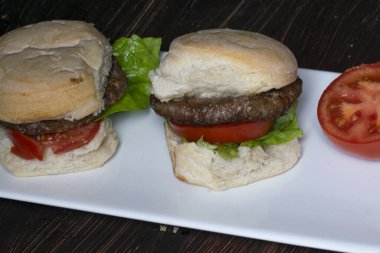 Hamburger, domates ve marullu, tabakta, masada.