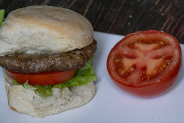 Hamburger, domates ve marullu, tabakta, masada.