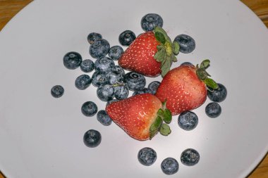 Beyaz tabakta çilek ve yaban mersini.