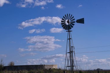 Yel değirmeni ve su birikintisi, mavi gökyüzünün altında