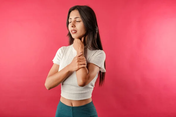 Young caucasian woman wearing casual top isolated over red background holding her inflamed throat. Medical concept, Sore throat. Having sore throat, holding hand on her neck, suffering from throat pain, painful swallowing.
