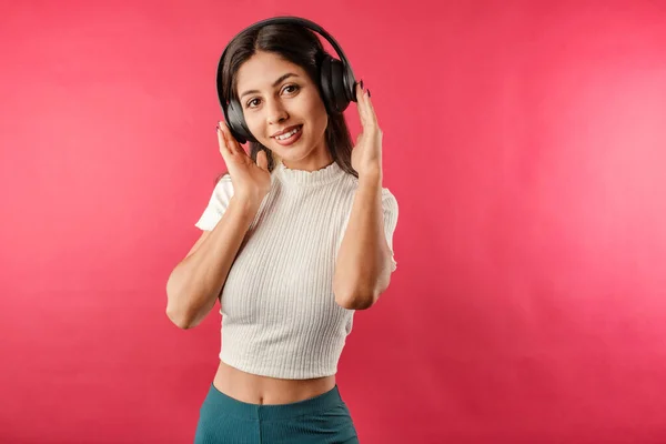 Kırmızılı kırbaç giyen genç ve güzel bir kadın kulaklıklara dokunarak hoş bir şekilde müzik dinliyor. Çok mutluyum, en sevdiğim müziği dinliyorum. Kameraya bakıyorum.