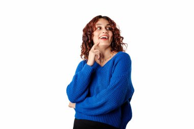 Beautiful woman standing isolated over white background touching cheek with index finger, laughs and looks at the empty copy corner. Thoughtful and decided what wants. Looks at the ads space.