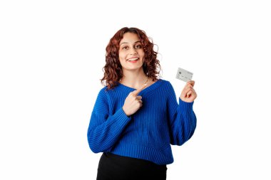 Young beautiful woman wearing pullover sweater isolated over white background pointing index finger at credit card. Demonstrating bank card solution. Showing it with a confident and proud expression.