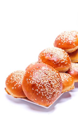 Bir tabak beyaz arka planda susam tohumlu bir sürü çörek.