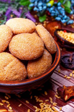 Kil tabakta ev yapımı kurabiye, kaşıkta buğday, kurumuş meyve, kahverengi arka planda bitki ve böğürtlen.