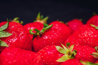 Siyah arka planda bir sürü taze çilek.