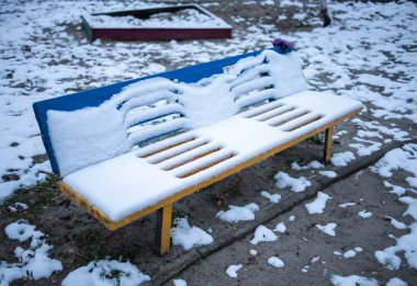 Kış bahçesindeki bankta karla kaplı.