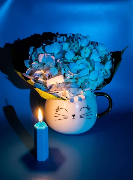 Mavi renkli, fincanda ortanca çiçeği ve yanan mum olan bir hayat.