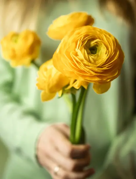 Elinde bir buket ranunculus çiçeği tutarken