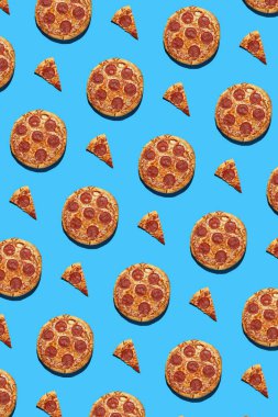 Bütünün sert ışık deseni ve pürüzsüz parlak mavi arka planda salam pizza parçaları, üst görünüm, dikey