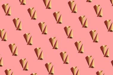 Parlak pembe arka planda boş bir waffle dondurma külahının sert ışık deseni, düz yatış, üst görünüm