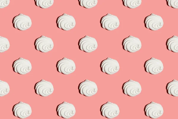 A hard light pattern of a sweet meringue dessert pavlova on a bright colorful pink seamless background, top view