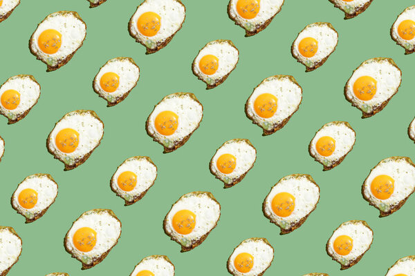 hard light pattern of a fried egg with unbroken egg yolk on a seamless green background
