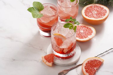 Greyfurtsuz alkolsüz kokteyl hazırlama - mermer yüzeyinde buz küpleri ve taze naneli birkaç bardak