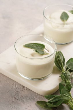 Kremalı süt yoğurdu tatlı kremalı krema, krem peynir, adaçayı ve limon suyu mermer tepside.