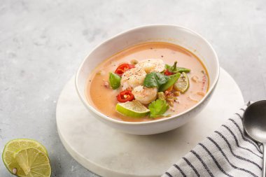 Hindistan cevizi çorbası ya da Hindistan cevizi sütü, kiraz domatesleri, bezelye, kırmızı biber, limon, zencefil, karides ve mermer kaplama üzerinde taze kişniş.