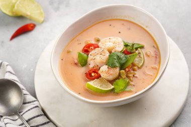 Hindistan cevizi çorbası ya da Hindistan cevizi sütü, kiraz domatesleri, bezelye, kırmızı biber, limon, zencefil, karides ve mermer kaplama üzerinde taze kişniş.