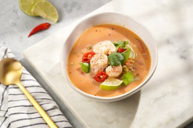 Hindistan cevizi çorbası ya da Hindistan cevizi sütü, kiraz domatesleri, bezelye, kırmızı biber, limon, zencefil, karides ve mermer kaplama üzerinde taze kişniş.