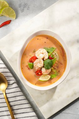 Hindistan cevizi çorbası ya da Hindistan cevizi sütü, kiraz domatesleri, bezelye, kırmızı biber, limon, zencefil, karides ve mermer kaplama üzerinde taze kişniş.