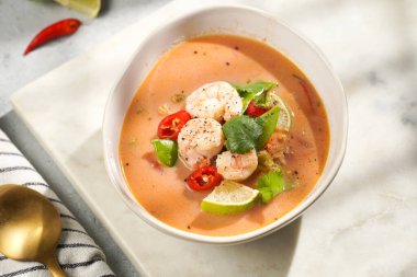 Hindistan cevizi çorbası ya da Hindistan cevizi sütü, kiraz domatesleri, bezelye, kırmızı biber, limon, zencefil, karides ve mermer kaplama üzerinde taze kişniş.