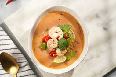 Hindistan cevizi çorbası ya da Hindistan cevizi sütü, kiraz domatesleri, bezelye, kırmızı biber, limon, zencefil, karides ve mermer kaplama üzerinde taze kişniş.