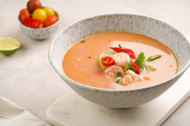 Hindistan cevizi çorbası ya da Hindistan cevizi sütü, kiraz domatesleri, bezelye, kırmızı biber, limon, zencefil, karides ve mermer kaplama üzerinde taze kişniş.