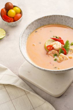 Hindistan cevizi çorbası ya da Hindistan cevizi sütü, kiraz domatesleri, bezelye, kırmızı biber, limon, zencefil, karides ve mermer kaplama üzerinde taze kişniş.