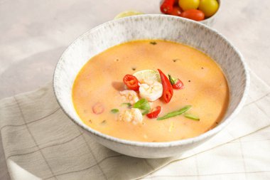 Hindistan cevizi çorbası ya da Hindistan cevizi sütü, kiraz domatesinden yapılmış köri, bezelye, biber, limon, zencefil, karides ve gri beton zeminde taze kişniş havlusu.